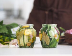 Borcane de sticlă cu murături de casă, cu mărar și usturoi, pe o masă de lemn
